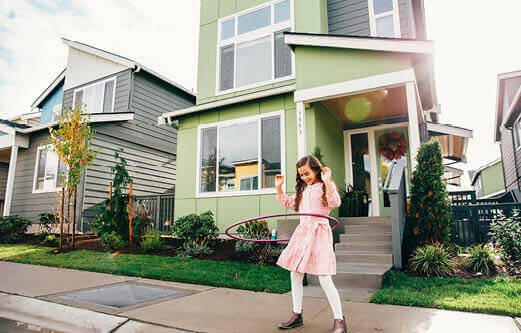 young girl hula hooping in front of a green house