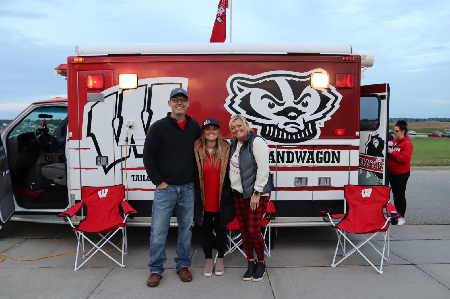 three people standing in front of an ambulance decorated with Wisconsin Badgers