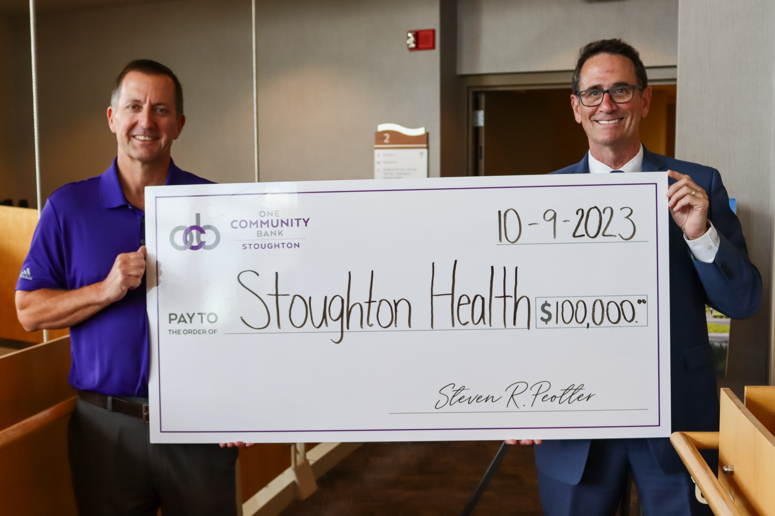 Steve Peotter and Dan DeGroot hold a big check to present OCB's donation of $100,000 to Stoughton Health