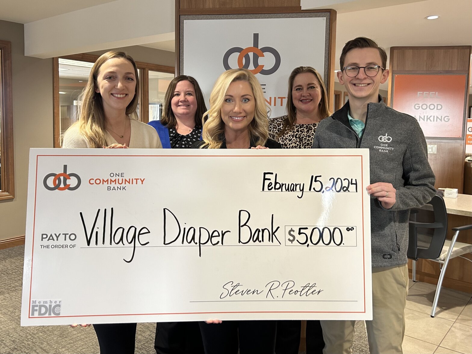 OCB colleagues present a big check photo to The Village Diaper Bank
