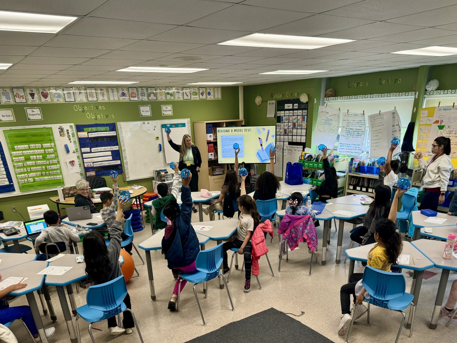 children holding up blue piggy banks in classroom