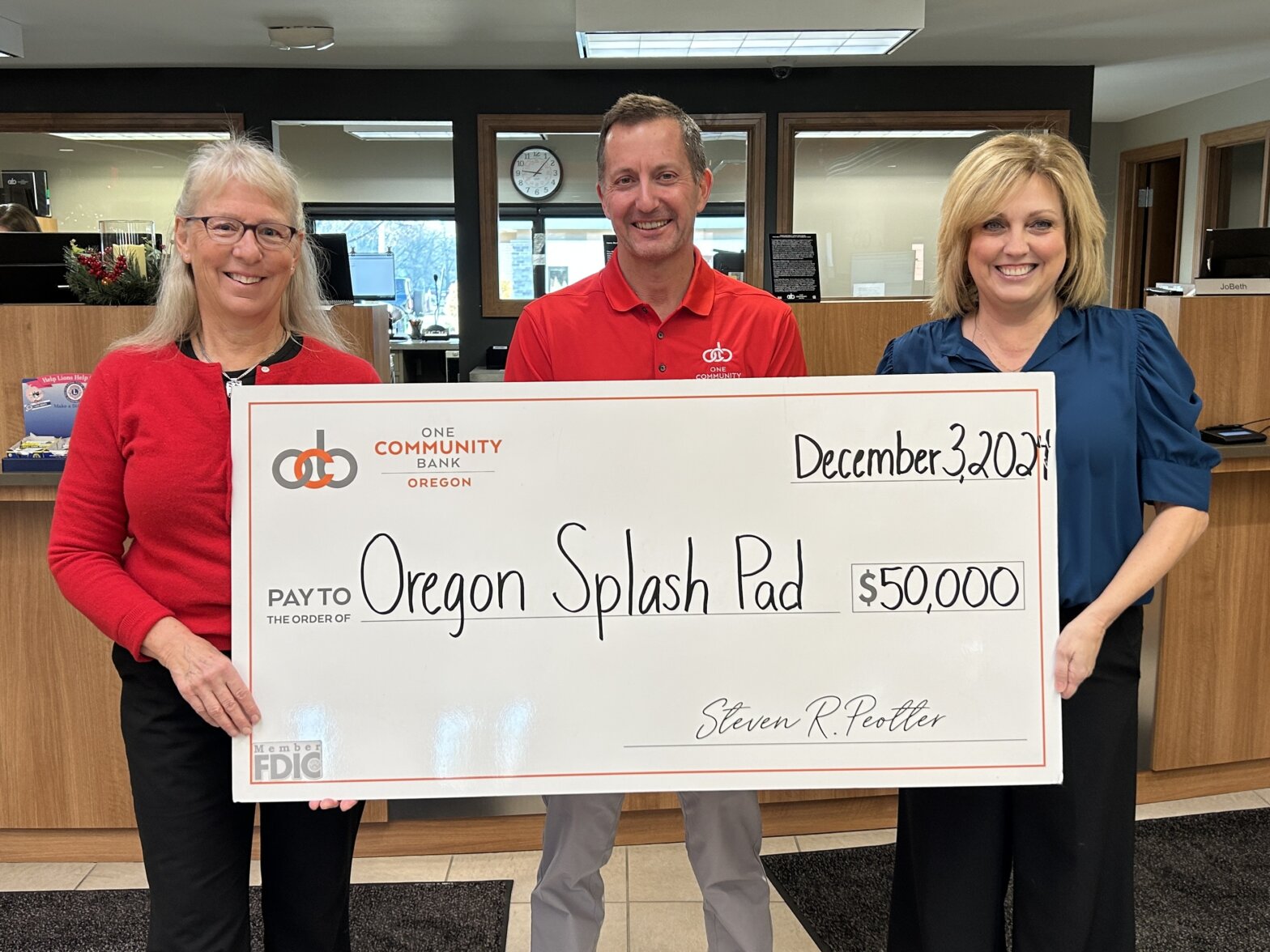 Steve Peotter, President and CEO with guests holding a big check