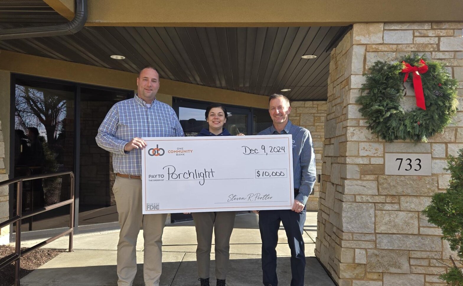 group of people standing with a big check to Porchlight