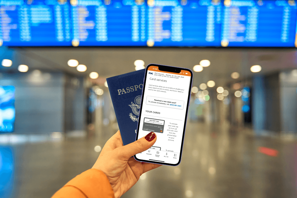 Persons hand holding up a phone and passport while in an airport.