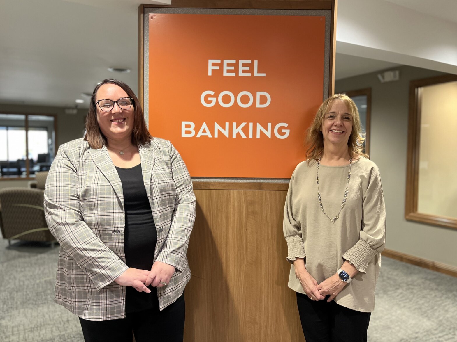 Melissa Lewis and Nona Havey standing in front of a Feel Good Banking sign