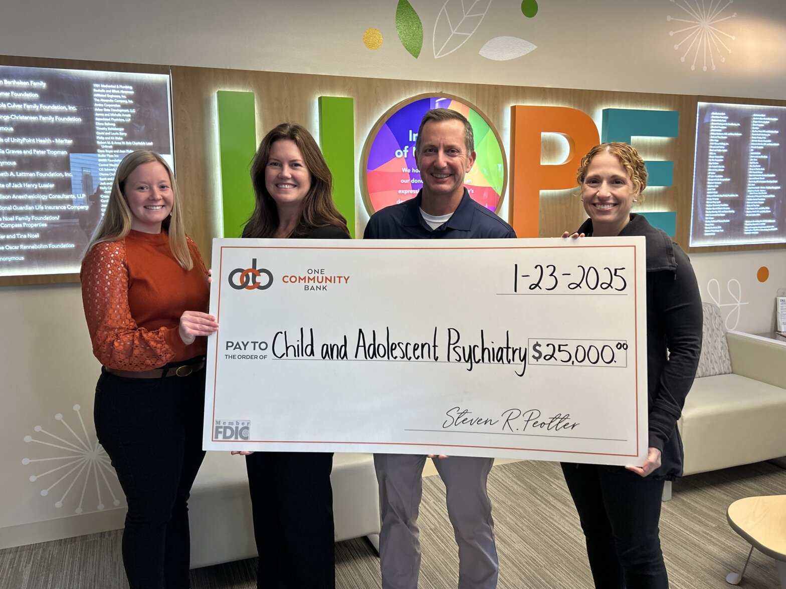 Group of people standing holding a big check