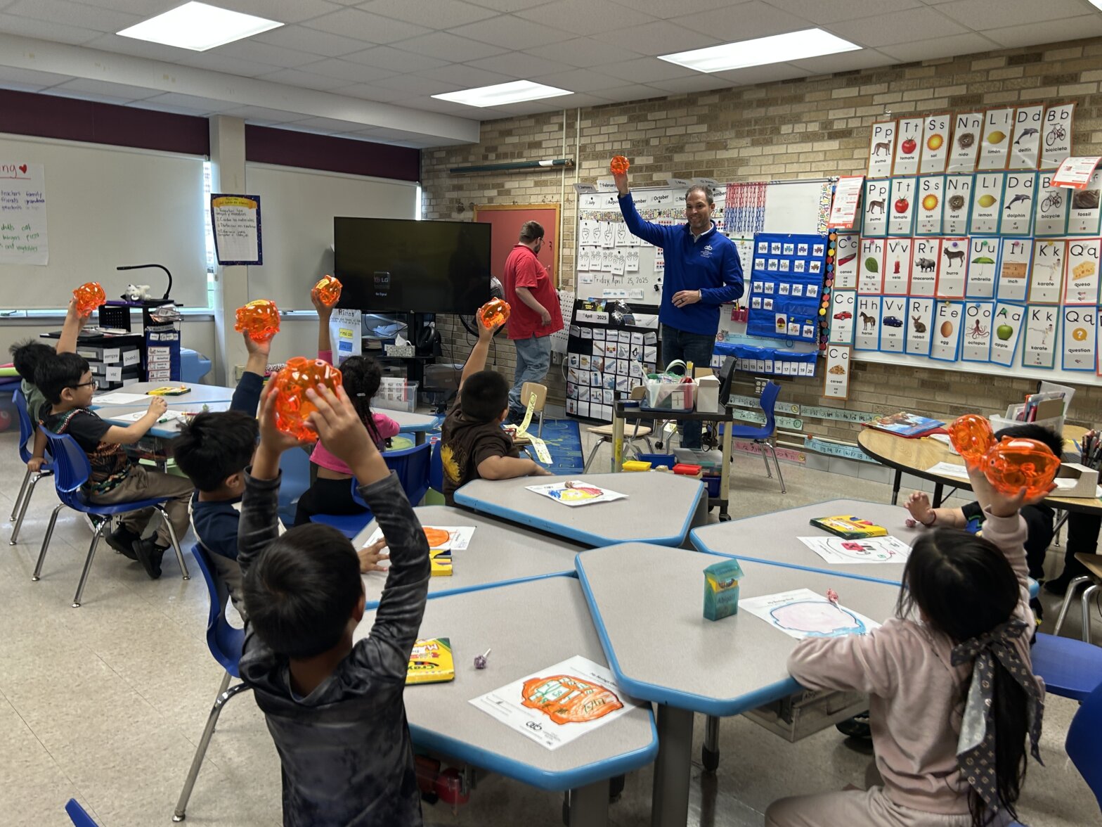 Classroom of children holding up piggy banks