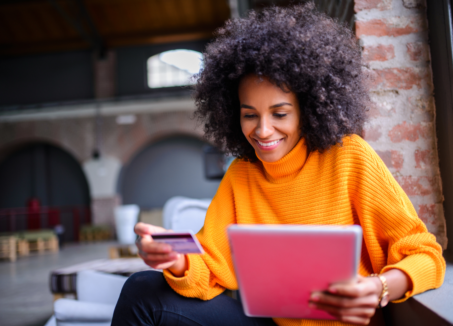 A women on her tablet, holding a credit card.